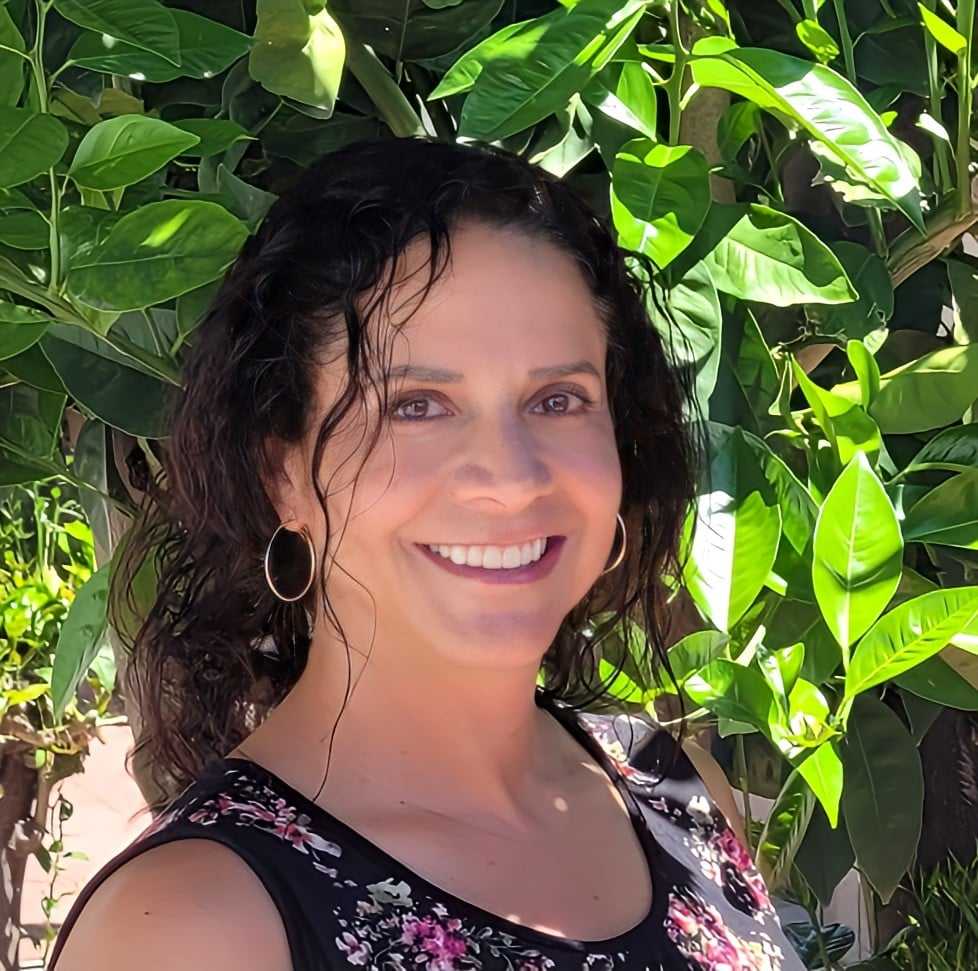 A woman standing in front of some trees
